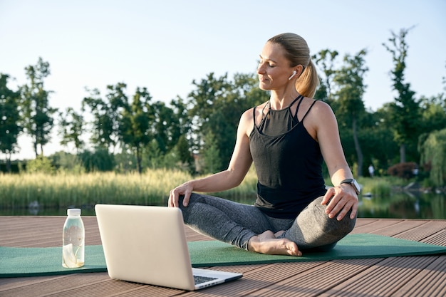 Tranquillité d'esprit belle femme d'âge moyen athlétique regardant des vidéos pédagogiques sur un ordinateur portable tout en