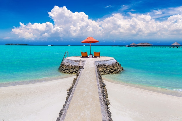 Transat et parasol sur la plage tropicale aux Maldives