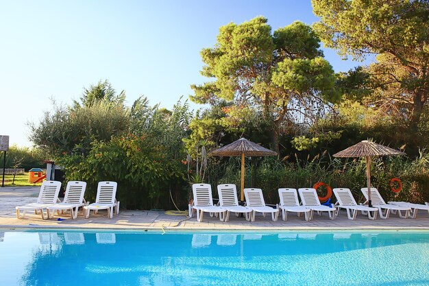 transats piscine journée ensoleillée, eau vacances d'été voyage