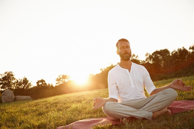 Transcendance au coucher du soleil Photo d'un bel homme mûr méditant à l'extérieur au coucher du soleil