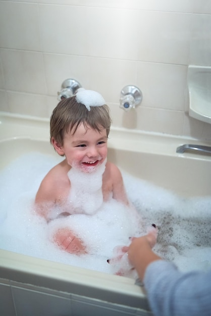 Transformer l'heure du bain en temps de jeu Photo recadrée d'un petit garçon assis dans une baignoire