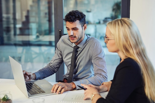 Transformer la productivité grâce au travail d'équipe Photo d'un jeune homme d'affaires et d'une femme d'affaires utilisant un ordinateur portable ensemble lors d'une réunion dans un bureau moderne