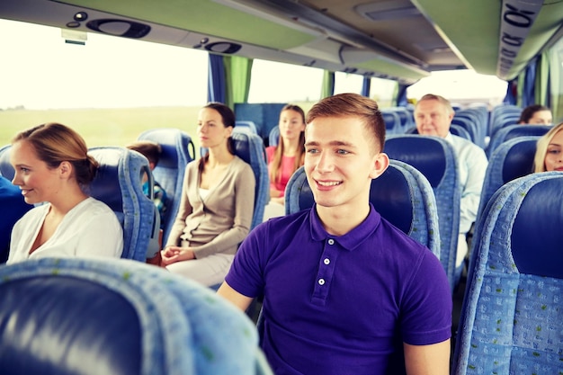 transport, tourisme, voyage sur la route et concept de personnes - jeune homme heureux assis dans un bus ou un train de voyage