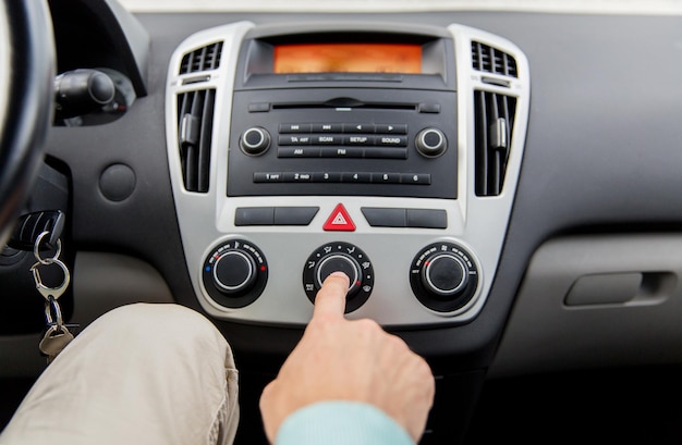 transport, voyage sur la route, conduite automobile, technologie et concept humain - gros plan d'une main masculine utilisant le contrôle climatique dans la voiture