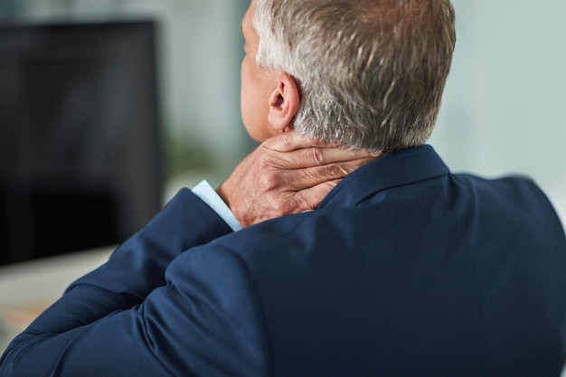 Transportant toute la tension dans son cou Vue arrière d'un homme d'affaires mature se frottant le cou au bureau