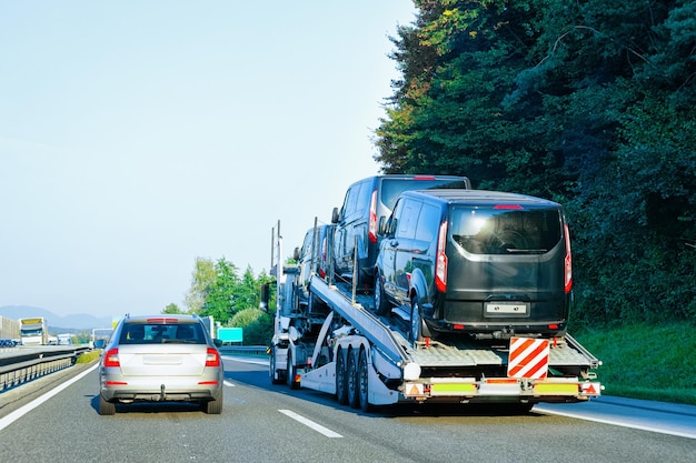 Transporteur de camions avec mini-fourgonnettes sur la route goudronnée, Slovénie.