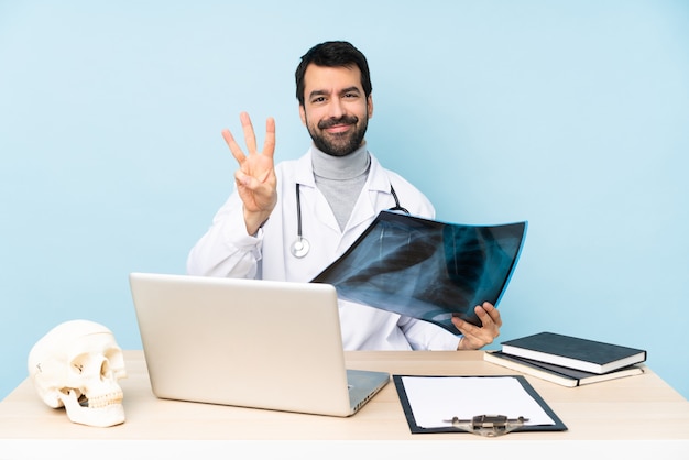 Traumatologue professionnel en milieu de travail heureux et comptant trois avec les doigts