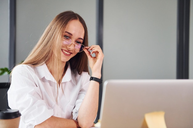 Travail actif Jeune femme adulte en vêtements formels est à l'intérieur au bureau