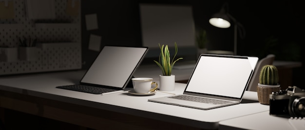 travail de bureau de style sombre espace de travail tard dans la nuit avec deux ordinateurs portables à écran blanc sur le bureau