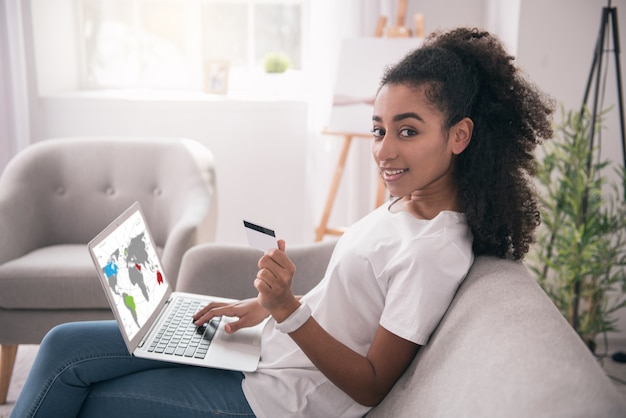 Photo travail à distance. belle femme intelligente travaillant en ligne et recevant son salaire sur la carte de crédit