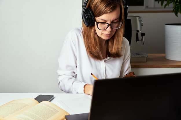 Travail à distance. Cours en ligne, enseignement à distance et concept d'apprentissage en ligne. Femme au casque écouter cours audio sur ordinateur portable