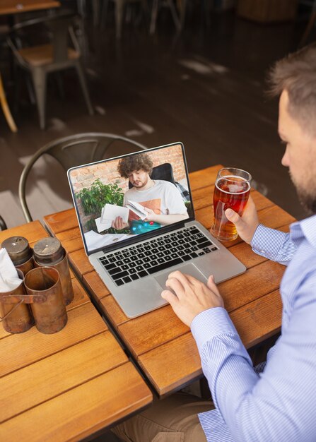 Travail à distance, divertissement en ligne pendant la quarantaine. Homme regardant un flux dans un bar, un restaurant avec un PC, des appareils et des gadgets. Concept d'apprentissage à distance, d'isolement, d'affaires, de shopping, de conférence.