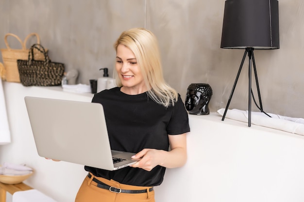 Travail à distance à domicile, indépendant pendant la quarantaine covid-19. Dame souriante assise et travaillant sur un ordinateur portable dans un intérieur confortable de salon, espace libre.