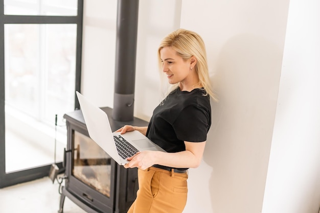 Travail à distance à domicile, indépendant pendant la quarantaine covid-19. Dame souriante assise et travaillant sur un ordinateur portable dans un intérieur confortable de salon, espace libre.