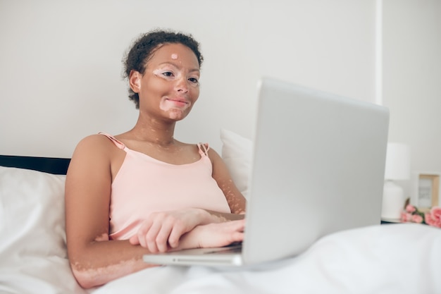 Travail à domicile. Une femme assise dans son lit et travaillant sur un ordinateur portable