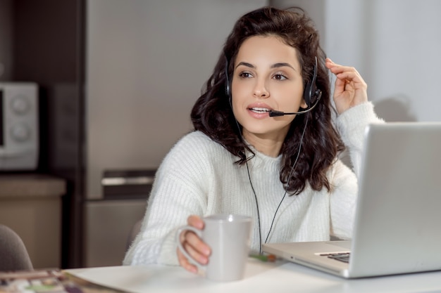 Travail à domicile. Une femme dans des écouteurs assis à l'ordinateur portable tout en travaillant à domicile