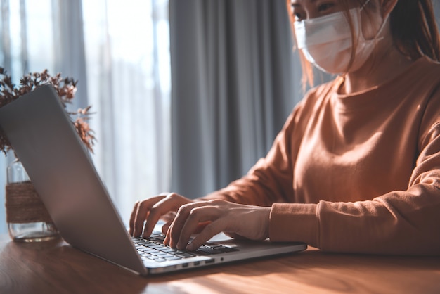 Travail à domicile, femme travaillant à domicile portant un masque de protection, virus Corona.
