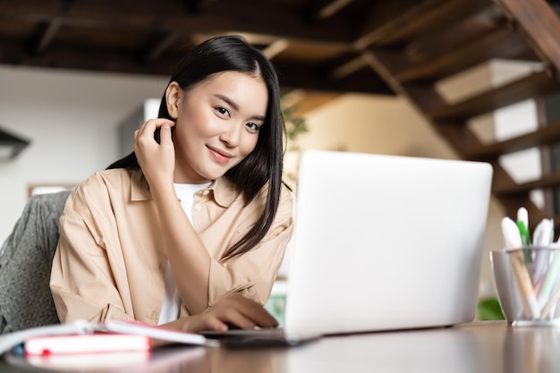 Travail à domicile fille asiatique utilisant un ordinateur portable et souriant étudiant à l'école en ligne