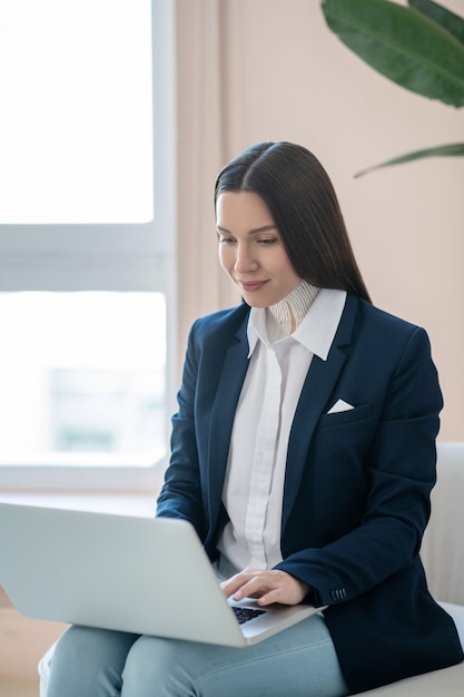 Travail à domicile. Jolie jeune femme aux cheveux noirs travaillant sur un ordinateur portable