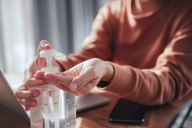 Travail à domicile, protection contre les coronavirus, gros plan se nettoyant les mains avec des gels désinfectants, femme en quarantaine pour coronavirus portant un masque de protection.