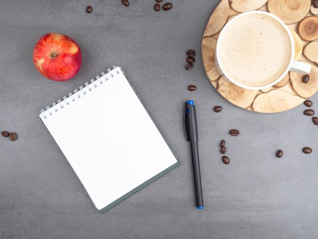 Travail du matin comme tasse de café grains de café pomme et stylo bloc-notes pour notes Concept de minimalisme