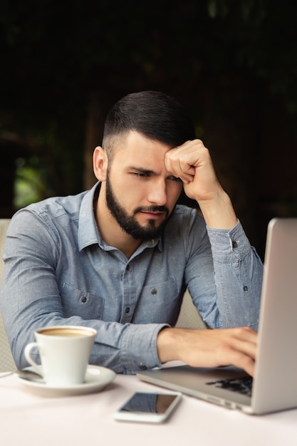 Travail dur à la maison. Homme malheureux tient sa tête