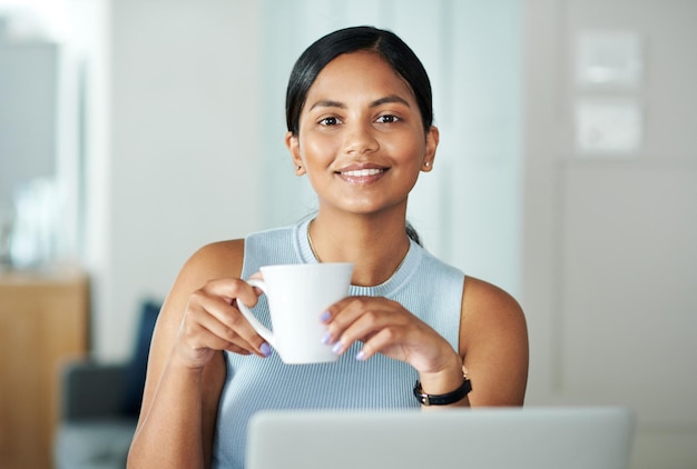 Le travail d'un entrepreneur n'est jamais terminé Photo d'une jolie jeune femme assise seule à son comptoir de cuisine et buvant du café