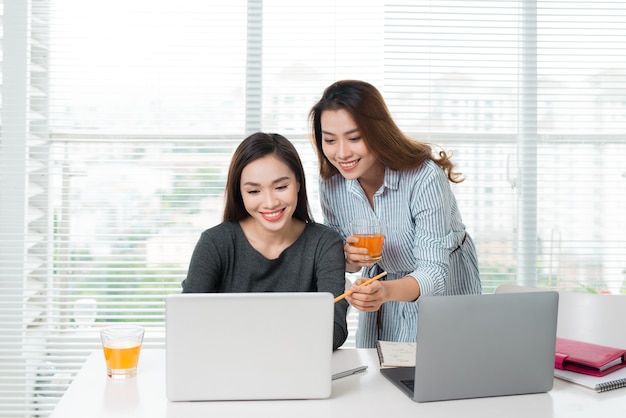 Travail en équipe. Deux jeunes femmes d'affaires souriantes assises au bureau à table et travaillant