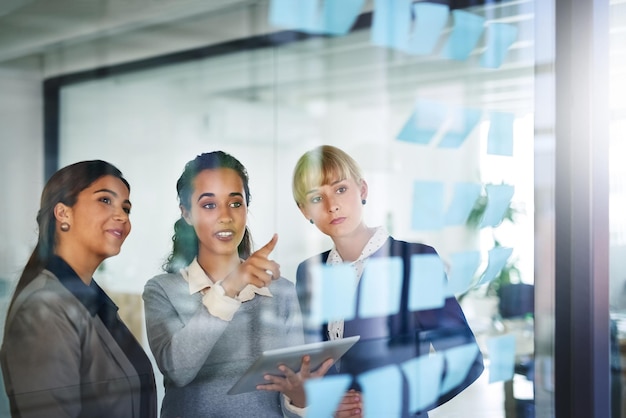 Photo travail d'équipe de gens d'affaires ou femmes créatives écrivant à bord pour réfléchir à des idées ou des objectifs de solution planification d'une note autocollante ou d'un groupe créatif parlant ou parlant ensemble