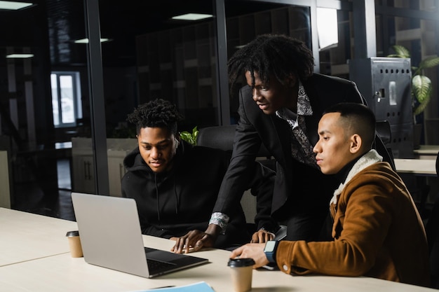 Travail d'équipe de groupe multiethnique d'employés noirs africains et asiatiques travaillant ensemble sur un ordinateur portable Discuter des processus commerciaux en équipe au bureau