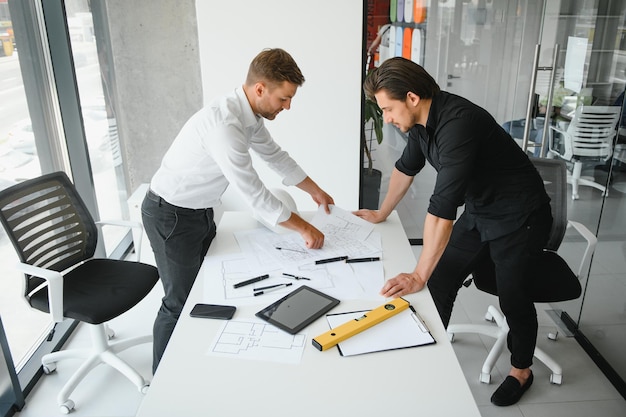 Travail d'équipe d'ingénieur ou d'architecte travaillant sur un projet de construction avec un modèle de construction et un plan dans le concept de construction de bureau