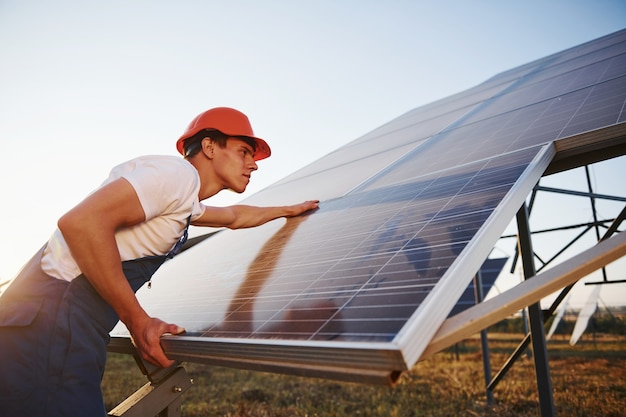 Travail manuel. Travailleur masculin en uniforme bleu à l'extérieur avec des batteries solaires aux beaux jours.