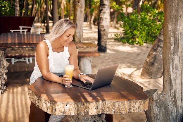Travail de pigiste par ordinateur portable dans un café tropical