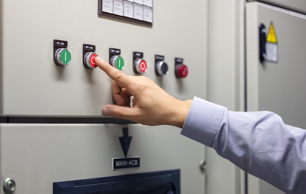 Travaillant dans la salle du centre de contrôle du système pour afficher diverses informations pour l'analyse des données dans l'industrie, une main actionne le bouton de contrôle du système du système automatique de commutation de couleurs.