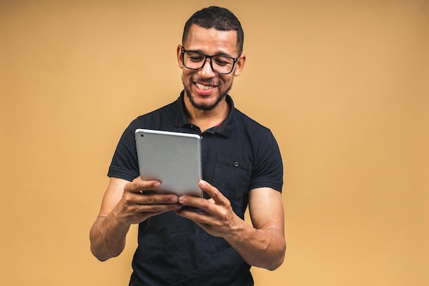 Travaillant sur une tablette numérique d'un jeune homme noir afro-américain souriant heureux tenant une tablette numérique