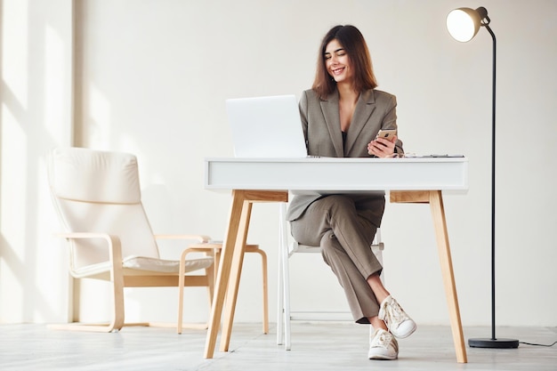 Travaille au bureau par ordinateur portable Jeune femme en vêtements formels est à l'intérieur Conception de style