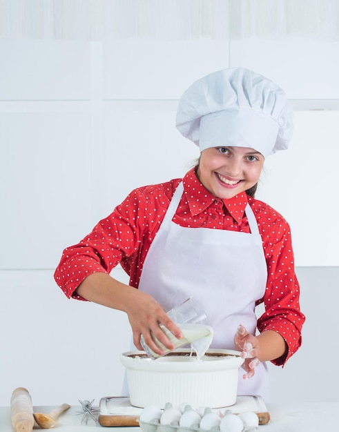 Travailler une alimentation saine et un concept de mode de vie fille faisant de la pâte à partir de farine et d'œufs régime et santé école culinaire cuisine traditionnelle enfant s'amusant avec de la nourriture à la cuisine enfant et cuisson