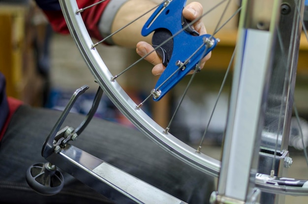 Travailler dans un atelier de réparation de vélos dans la main tient l'instrument pour tendre les rayons