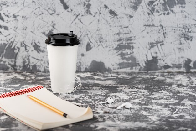 Travailler en déplacement. Tasse à café et bloc-notes sur table en pierre grise. Copiez l'espace.