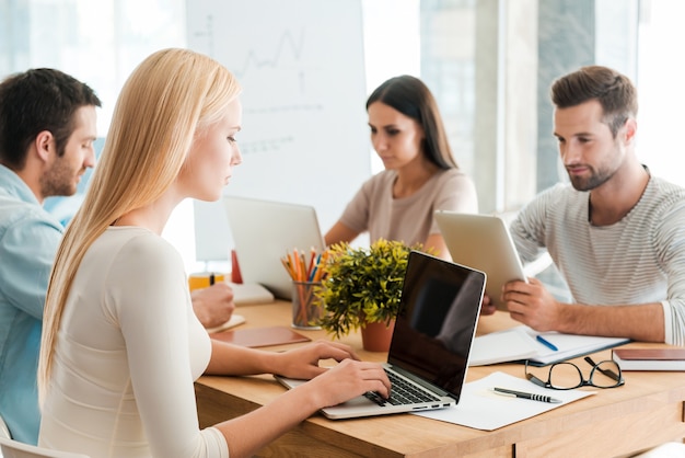 Travailler ensemble sur un nouveau projet. Groupe d'hommes d'affaires confiants dans des vêtements décontractés intelligents travaillant ensemble tout en étant assis au bureau au bureau