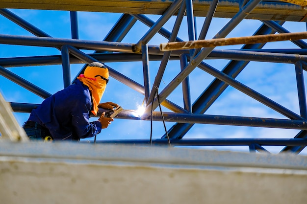 travailler en hauteur, homme soudant la structure du toit d&#39;usine dans le chantier de construction