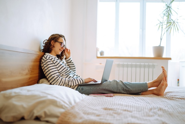 Travailler en ligne Jeune pigiste assise à la maison et travaillant sur un ordinateur portable Achats en ligne