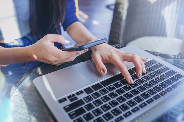 Travailler à la maison. femme textos un massage sur téléphone mobile et connexion réseau par ordinateur portable.