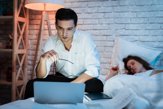 Travailler sur un ordinateur portable au lit avec une jeune femme.