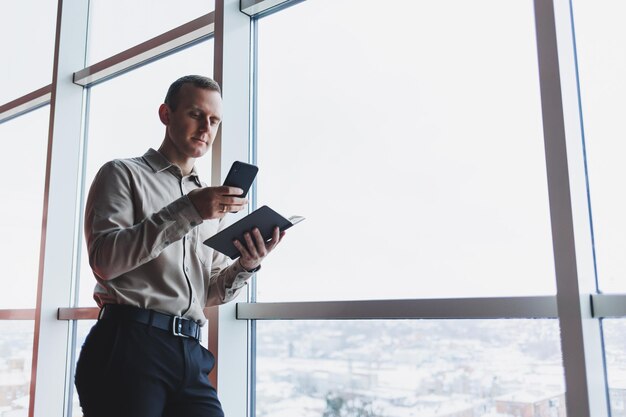 Travailler avec des papiers Homme entrepreneur sérieux travaillant au bureau seul lisant un document sur papier en pensant aux termes Jeune homme concentré faisant de la paperasse accord d'édition tex