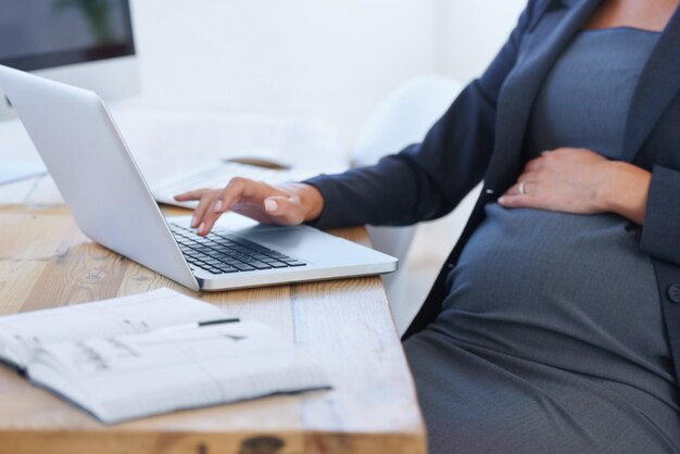 Travailler pour l'avenir du bébé Image recadrée d'une femme d'affaires enceinte travaillant sur son ordinateur portable au bureau