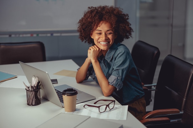 Travailleur afro-américain souriant assis sur le lieu de travail