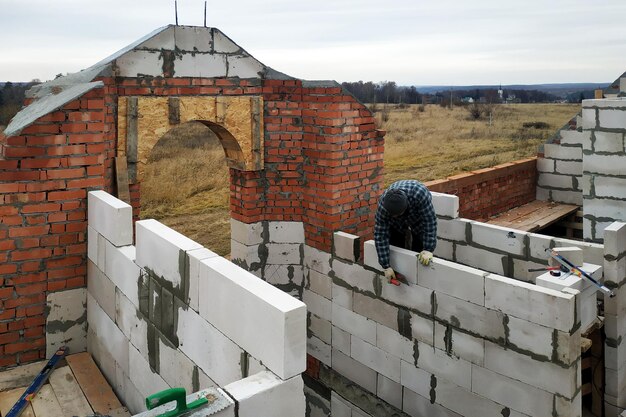 Le travailleur amarrant le mur des blocs d'ordures utilise la solution adhésive du niveau de la truelle