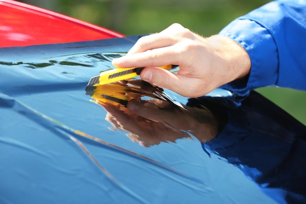 Travailleur appliquant une feuille de teinture sur la fenêtre de la voiture