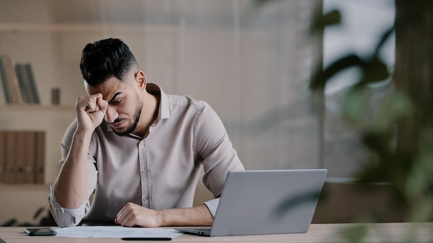 Un travailleur arabe mécontent et choqué regarde l'écran d'un ordinateur portable, se sentant nerveux et contrarié par de mauvaises nouvelles
